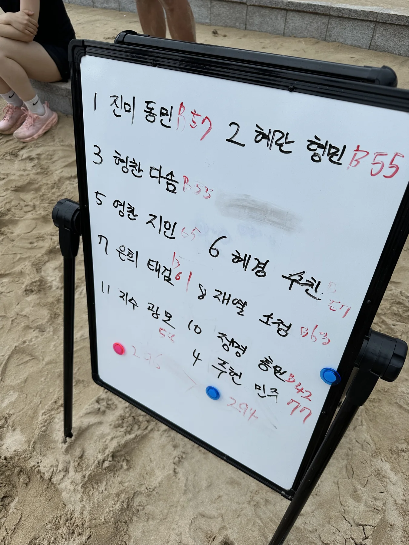 홀수 팀과 짝수 팀의 버피 기록이 적힌 해변 WOD 화이트보드